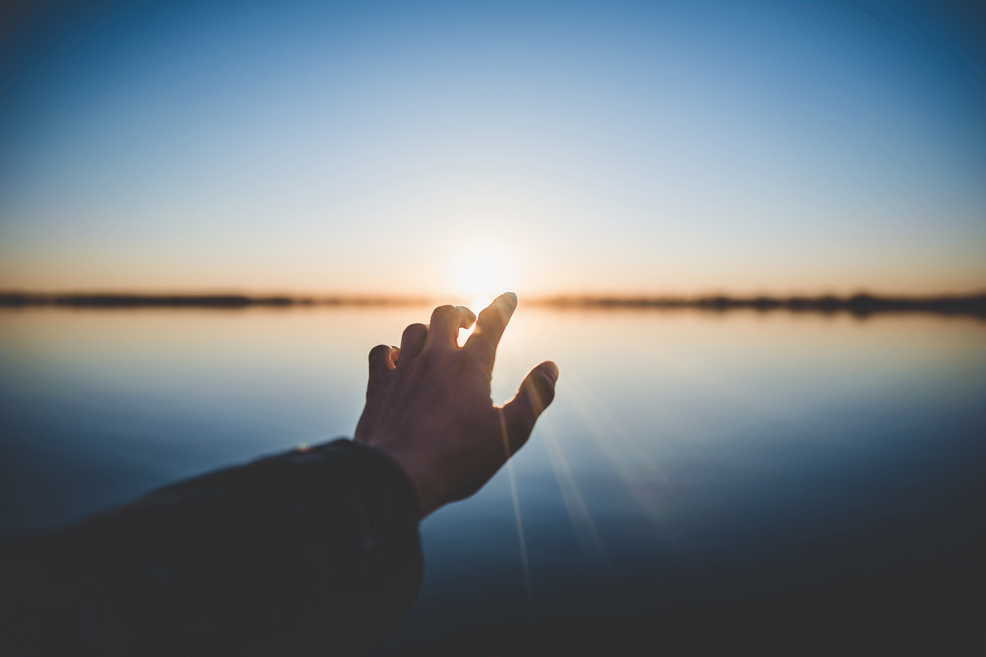 hand reaching towards sunset