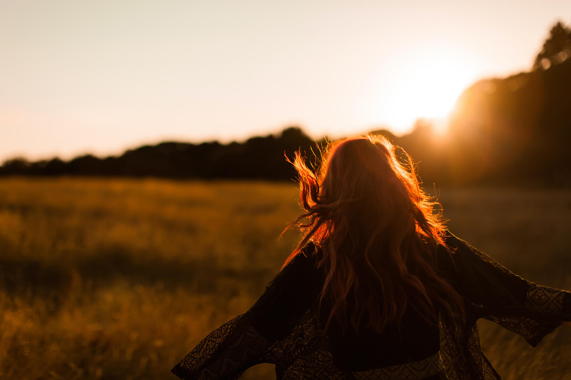 woman running through field at sunset